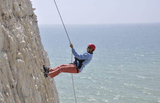 A photo of a person abseiling down the Peacehaven Cliffs
