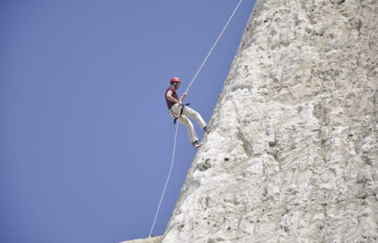 A photo of a person abseiling down the Peacehaven Cliffs